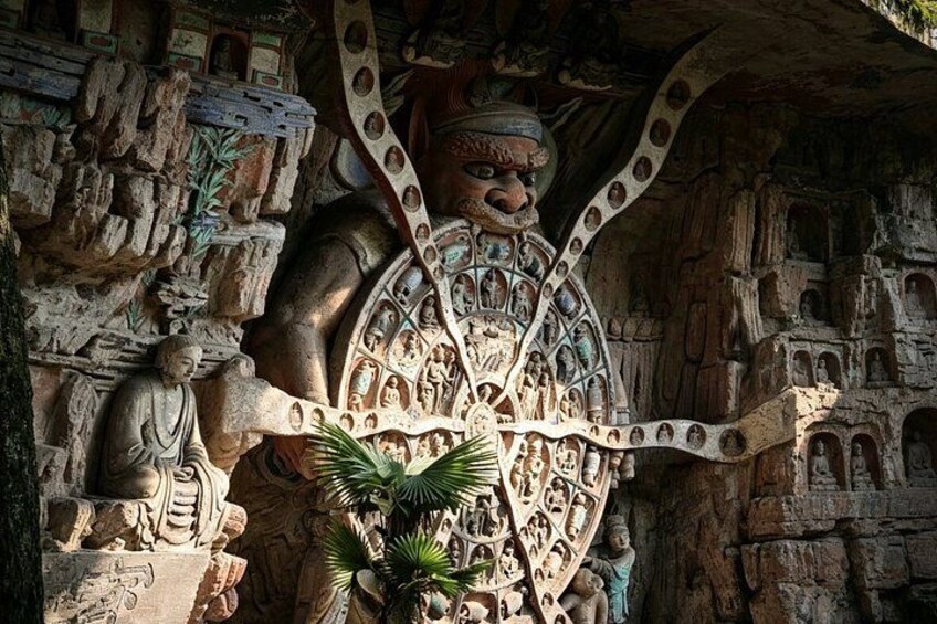 A large stone sculpture with intricate carvings, including a central figure with outstretched arms and surrounding smaller figures. 5