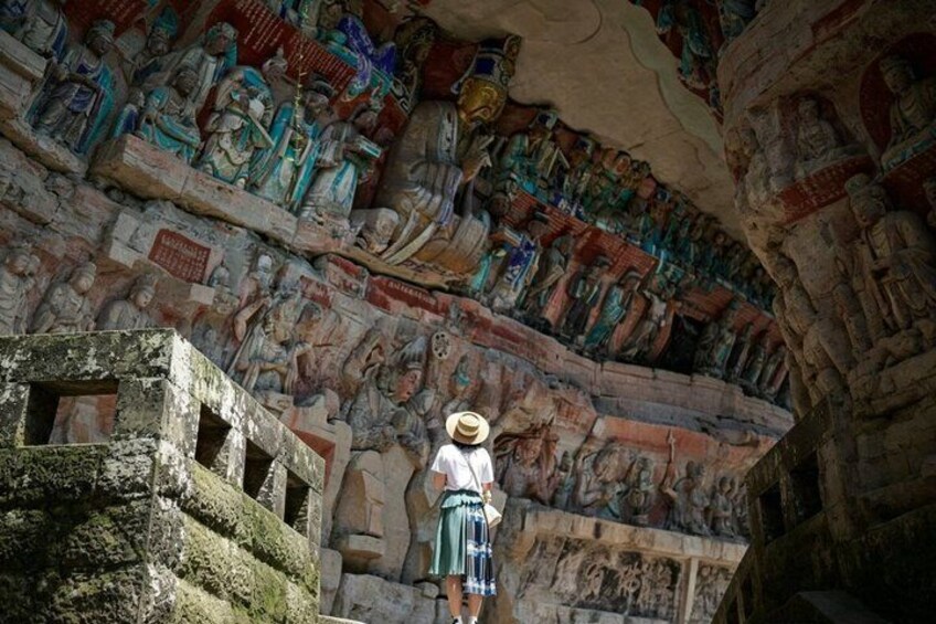 A person standing in front of a detailed stone wall with carvings. 3