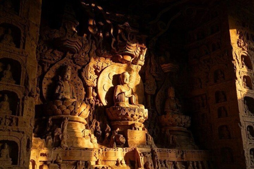 A detailed stone carving of a seated figure, surrounded by smaller figures and intricate designs. 4