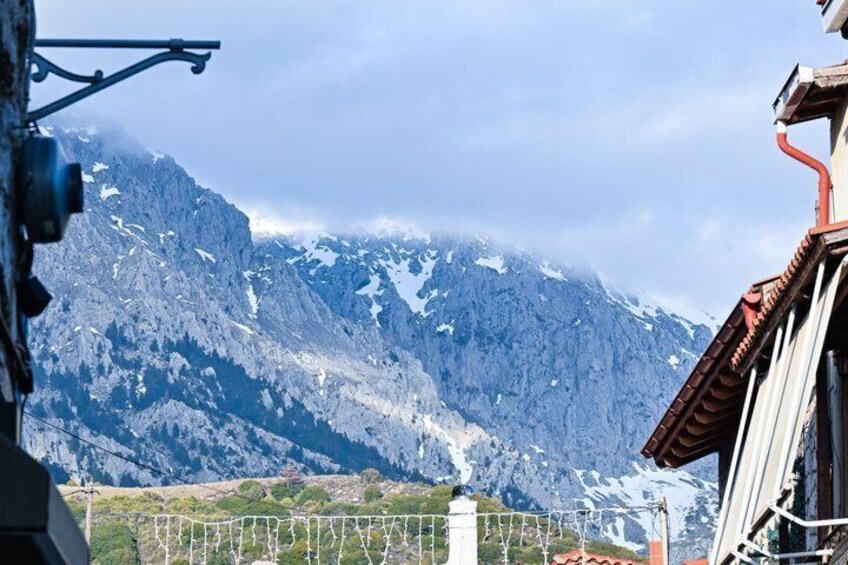 A mountain range with snow-capped peaks, a clear sky, and a building with a red roof in the foreground. 4
