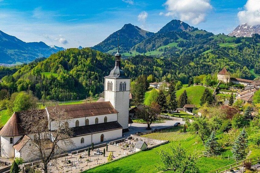 A church surrounded by a cemetery, with mountains in the background. 2