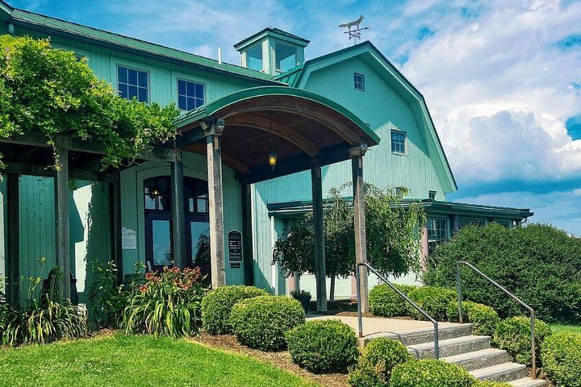 A large, green house with a covered porch, steps leading up to the entrance, and well-maintained landscaping. 1