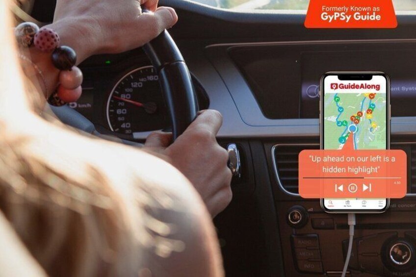 A person driving with a GPS device displaying a map and a message about a hidden highlight ahead. 1