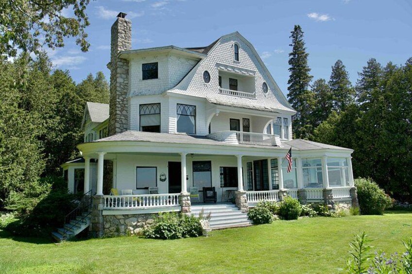 A large, two-story house with a stone chimney, white exterior, and a covered porch. 5
