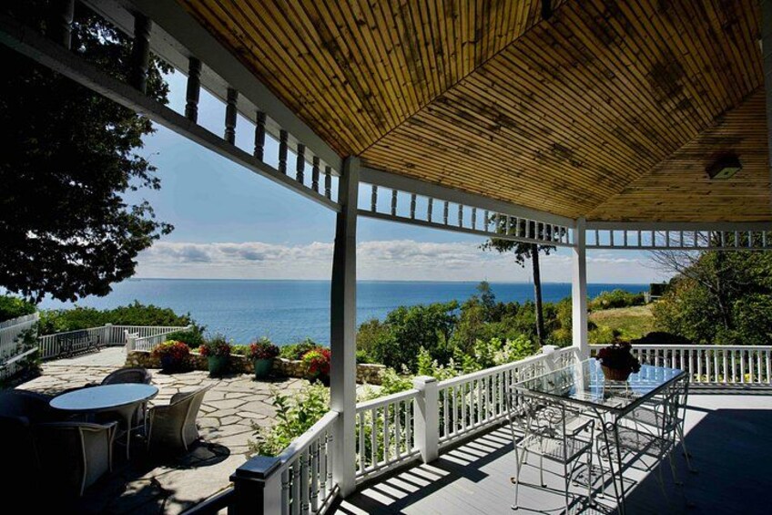 A covered patio with outdoor furniture, a railing, and a view of the ocean. 2