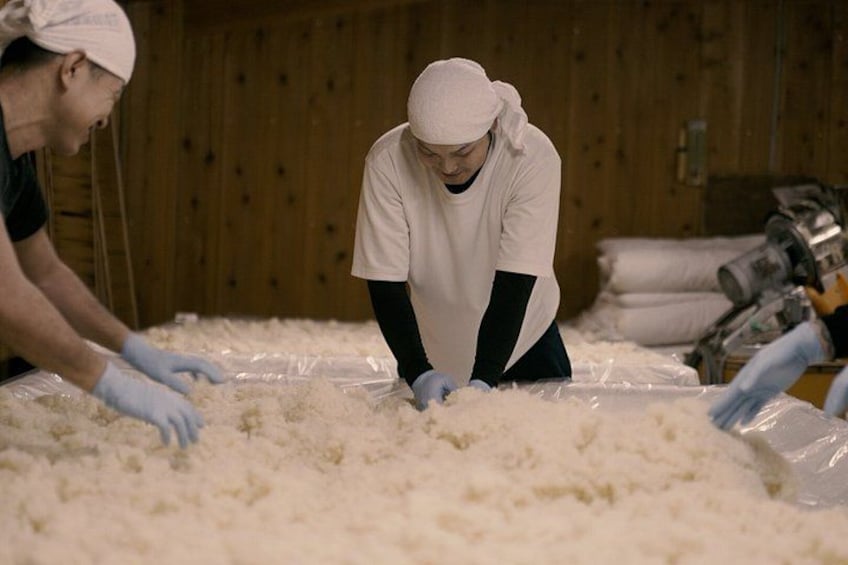 Two people working with a large quantity of white material on a table in a wooden room. 5