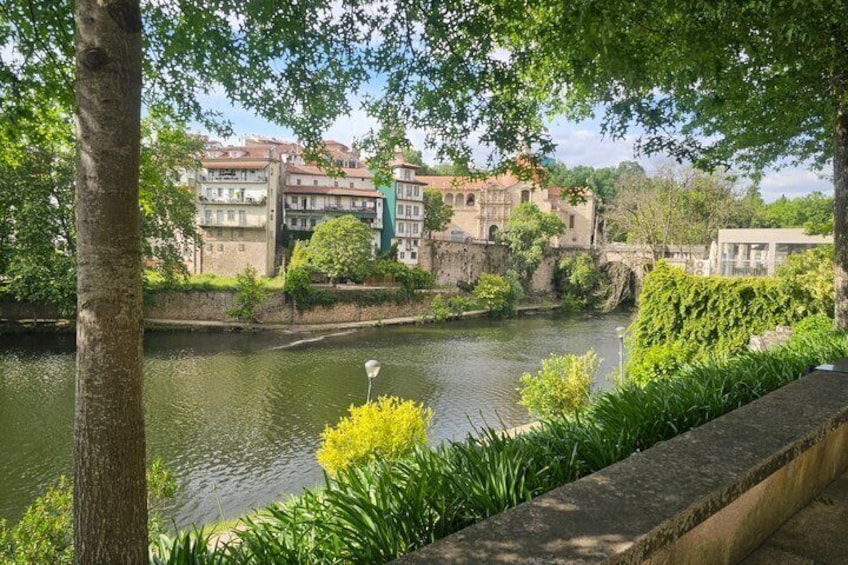 A river with buildings in the background, a tree in the foreground, and a stone wall. 3