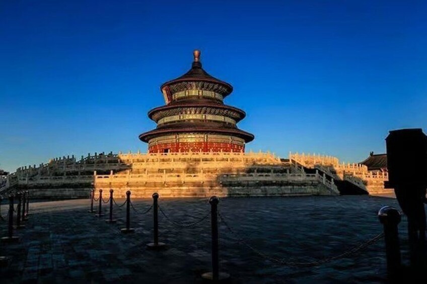 A traditional Chinese pagoda with a tiered roof, surrounded by a stone wall and a clear blue sky. 2