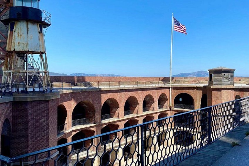 A brick bridge with arches, a metal fence, and an American flag. 3