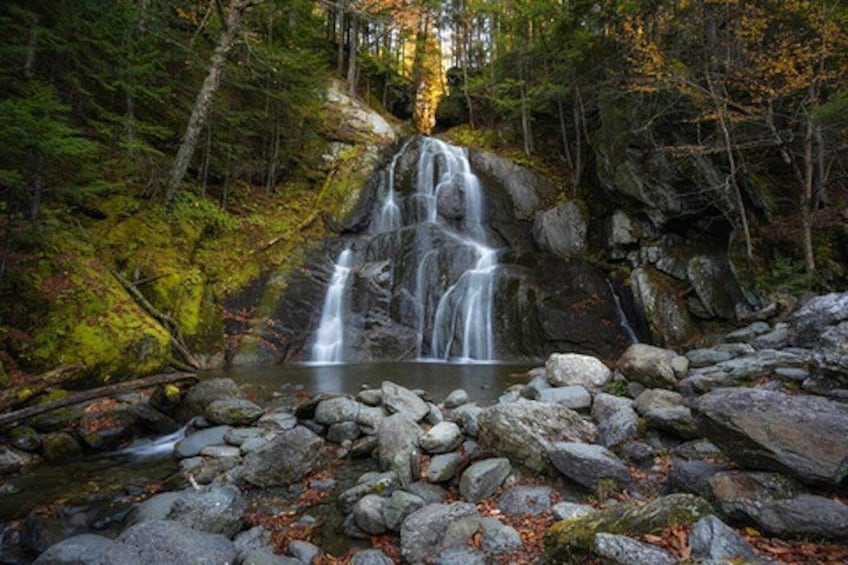 A waterfall surrounded by rocks and trees. 4