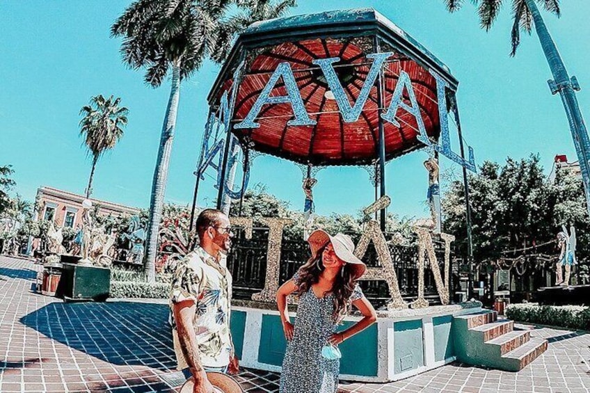 A man and a woman standing in front of a structure with the letters 'AVA' on it. 3