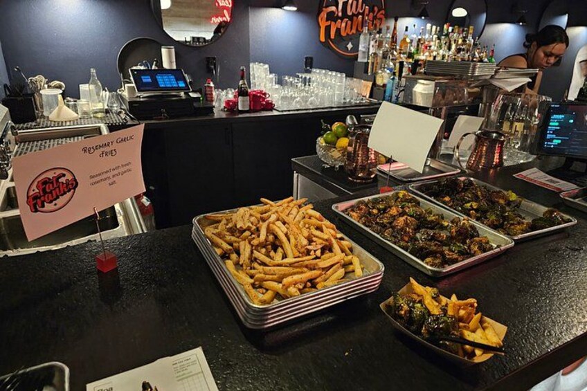 A food counter with various dishes, including fries and a sign for rosemary garlic fries. 5