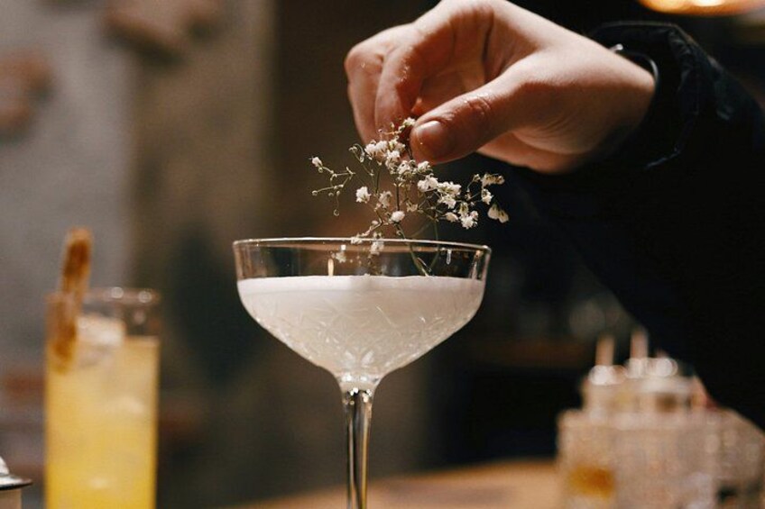 A hand placing flowers into a martini glass. 3