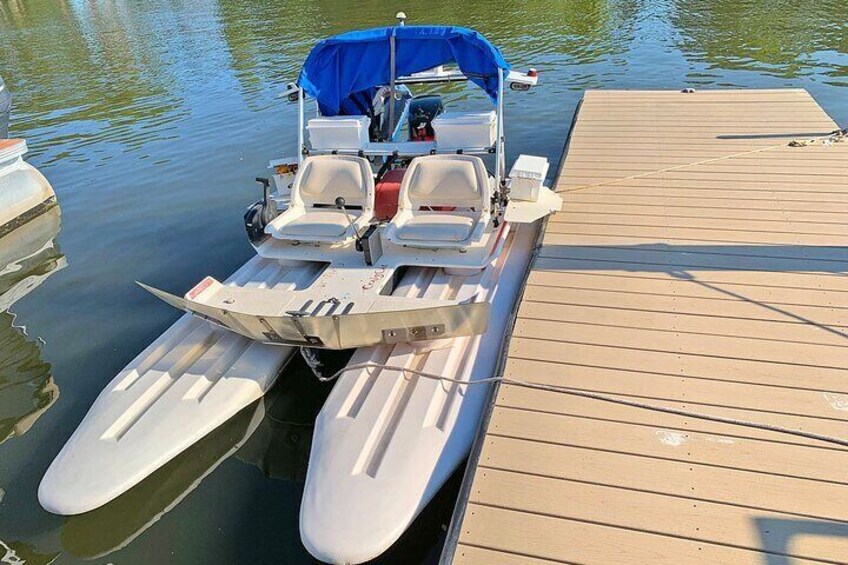 A small motorboat with a blue canopy and two white seats docked at a wooden pier. 5