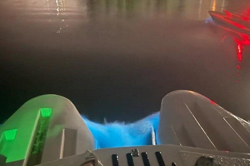 A boat's wake on water, a green object, and a red light. 1