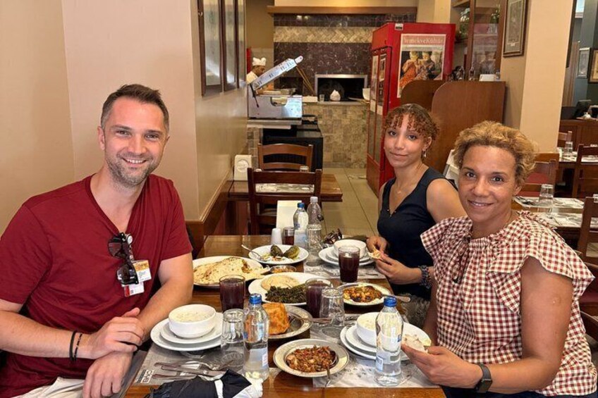 A group of people dining at a restaurant with various dishes and drinks on the table. 1