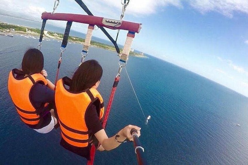 Two people in orange life jackets on a cable swing over a body of water. 1