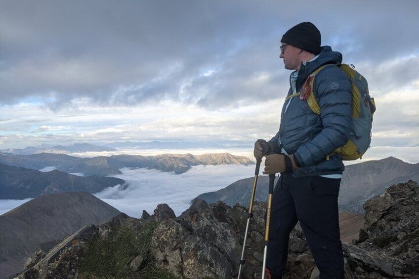 A hiker with a backpack and walking poles on a mountain ridge. 1