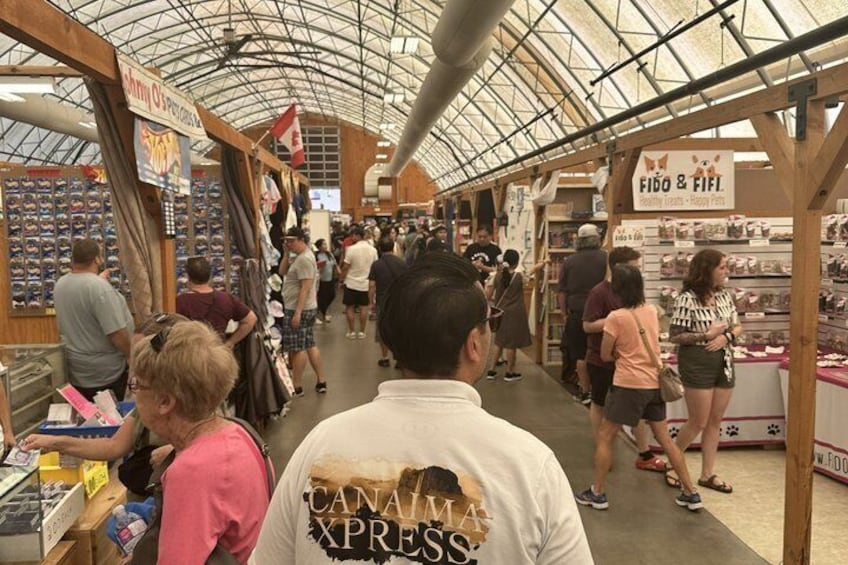 A busy indoor market with people shopping and vendors selling goods. 3