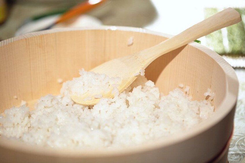A wooden bowl with white rice and a wooden spoon. 4