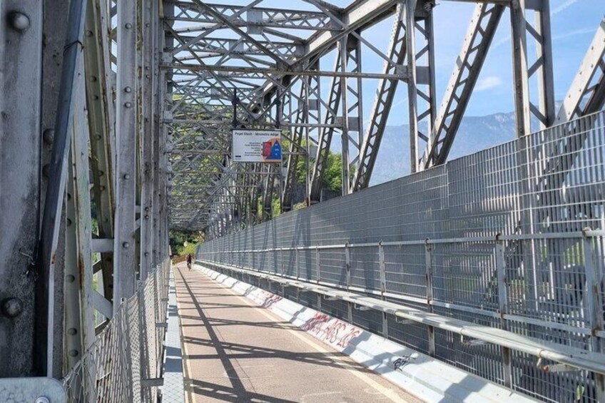 A metal bridge with a pedestrian walkway and a sign indicating a nearby attraction. 3