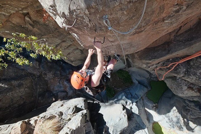 A person climbing a rock face with safety gear and ropes. 2