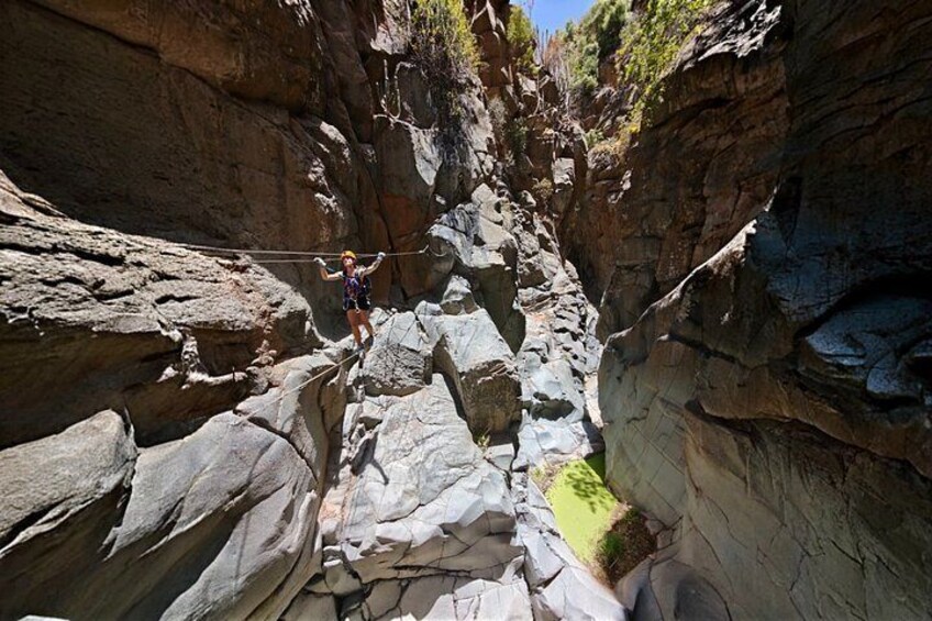 A person rappelling down a rocky canyon. 3
