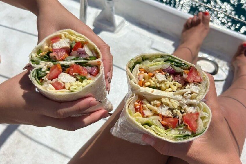 A person holding a wrap with visible ingredients like lettuce, tomatoes, and chicken. 5