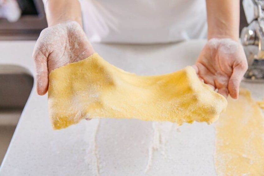 A person stretching dough on a floured surface. 1