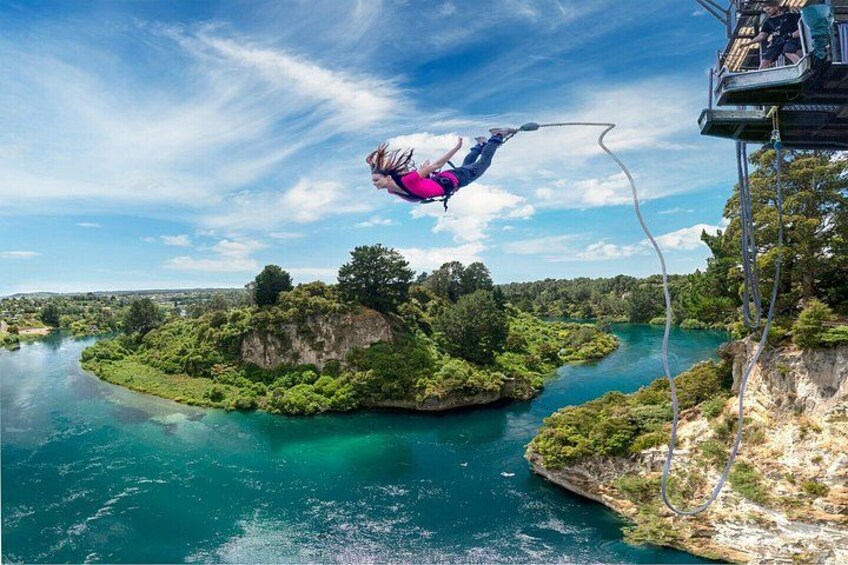 A person bungee jumping off a high platform with a river and greenery below. 4