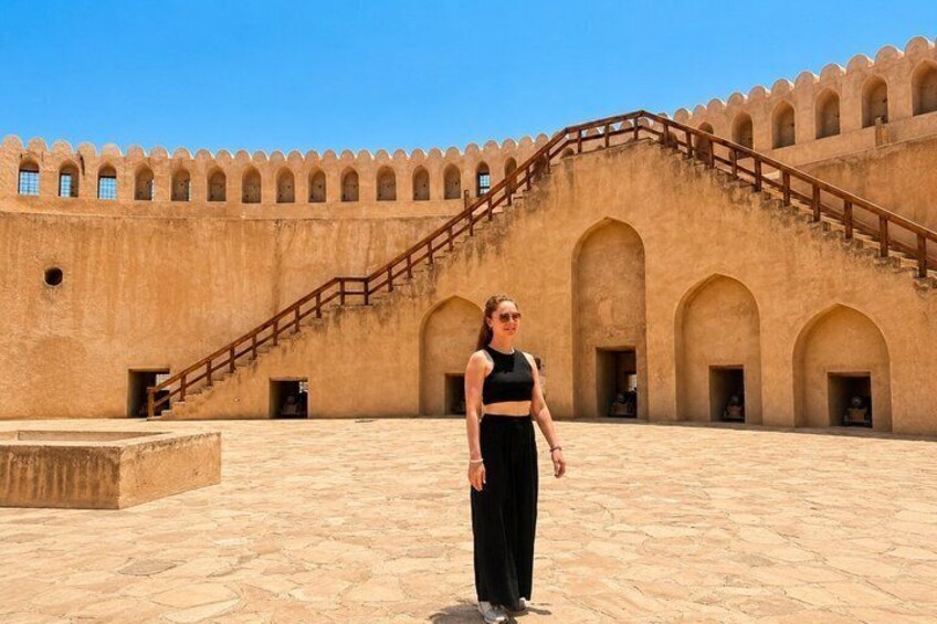 A person standing in front of a large, historic building with arched doorways and a staircase. 1