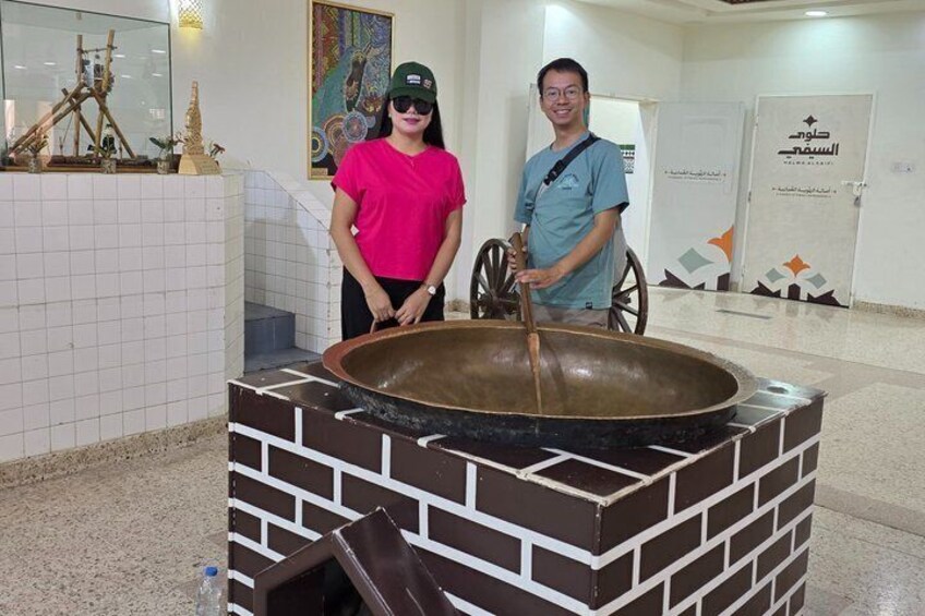 A person standing next to a large cooking pot on a brick structure. 3