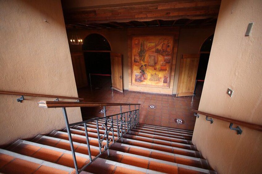 A staircase with metal railings, a tiled floor, and a mural on the wall. 2