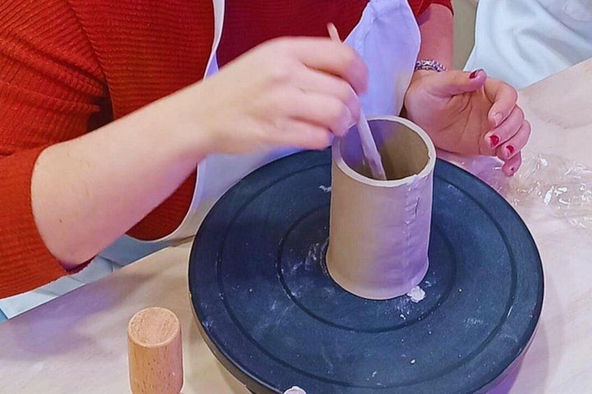 A person shaping a clay pot on a pottery wheel. 4