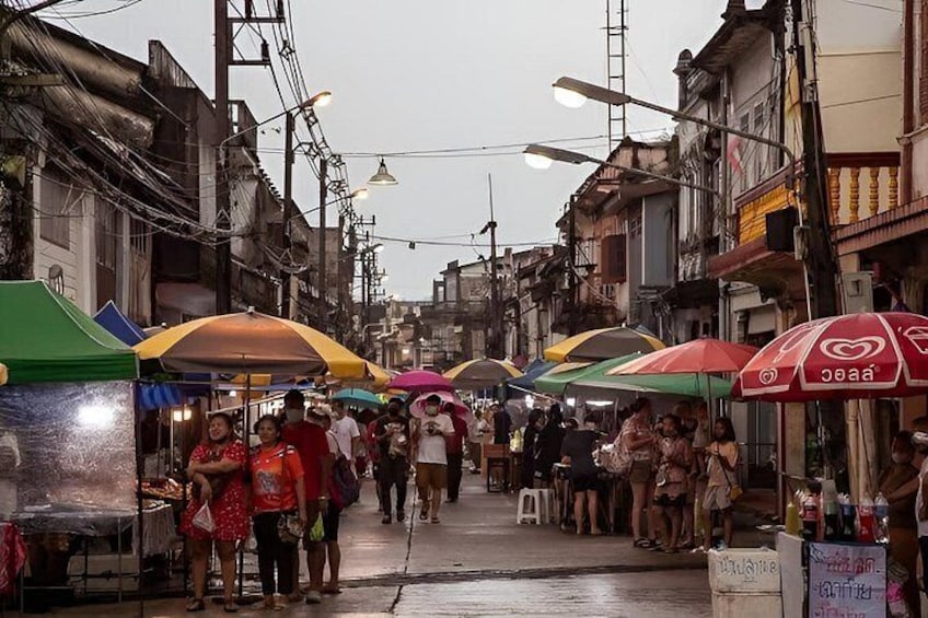 A crowded street market with people walking and vendors under colorful umbrellas. 3