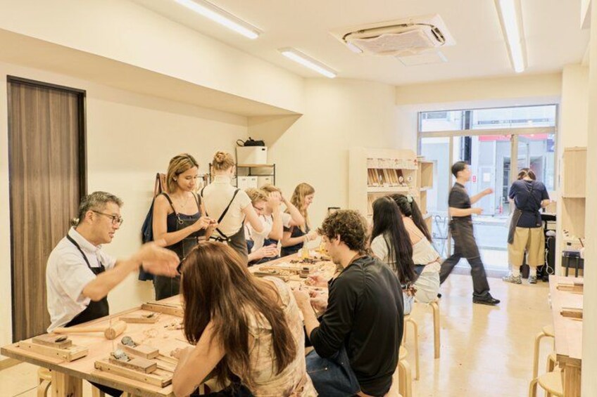 A group of people engaged in a workshop or class in a well-lit room with tables and chairs. 4