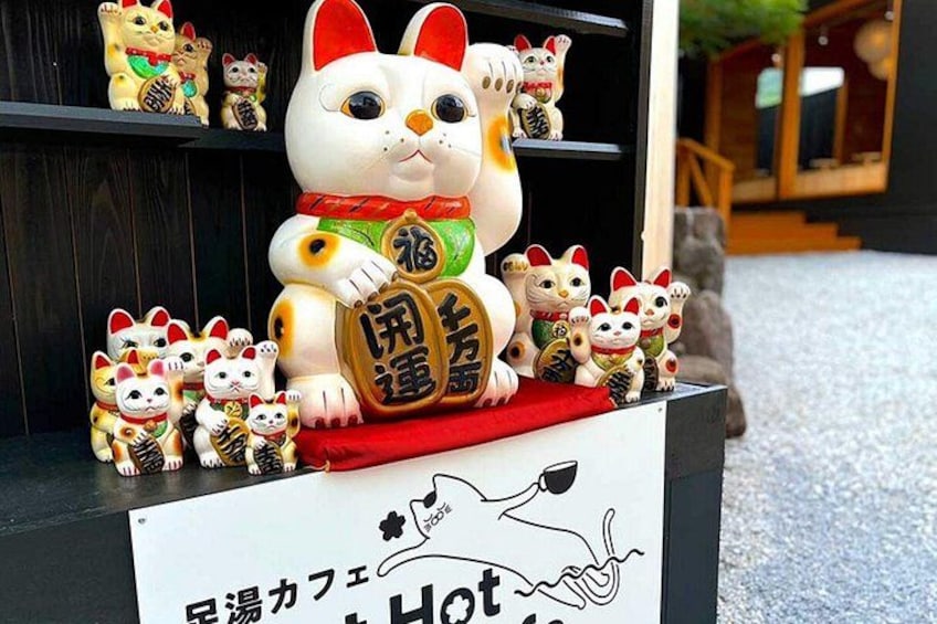A display of Maneki-neko figurines, including a large one with a red collar and a smaller one with a green collar, both with Japanese characters. 4