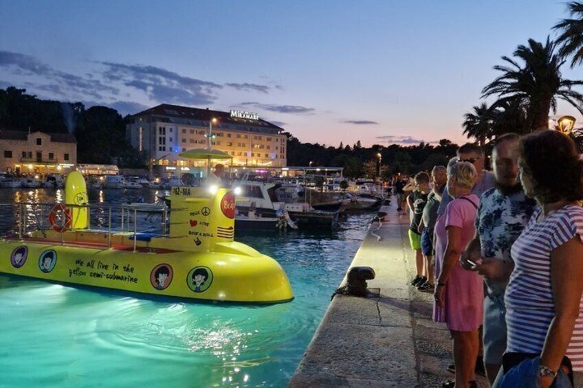 A yellow submarine-shaped boat with people standing on the dock. 2