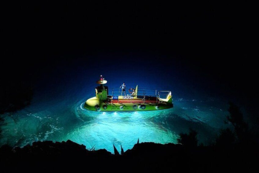 A large green and yellow ship floating on calm water at night. 4