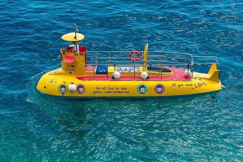 A yellow submarine with text and symbols on its side, floating on clear blue water. 1