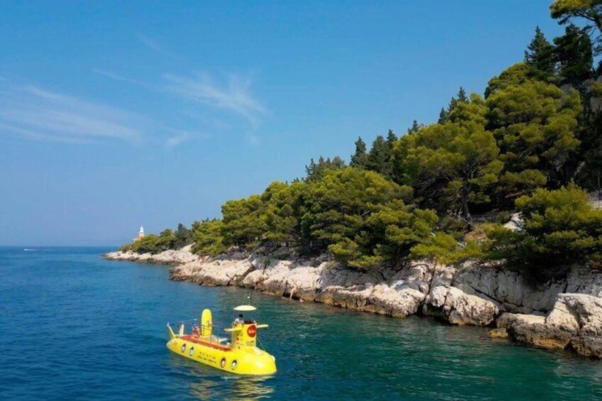 A yellow inflatable boat on calm blue waters, a rocky coastline with dense green trees, and a lighthouse in the distance. 5