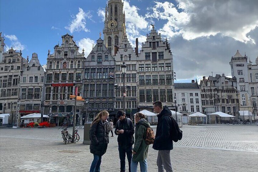 A group of people standing in a square with historic buildings in the background. 3