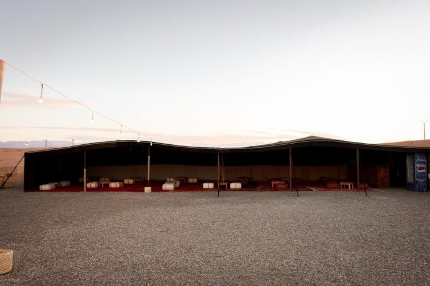 A large, open-air structure with a curved roof, possibly a warehouse or event space, with chairs arranged inside. 5