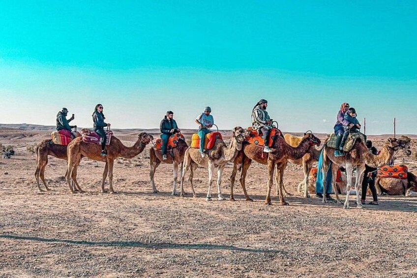 A group of people riding camels in a desert landscape. 2