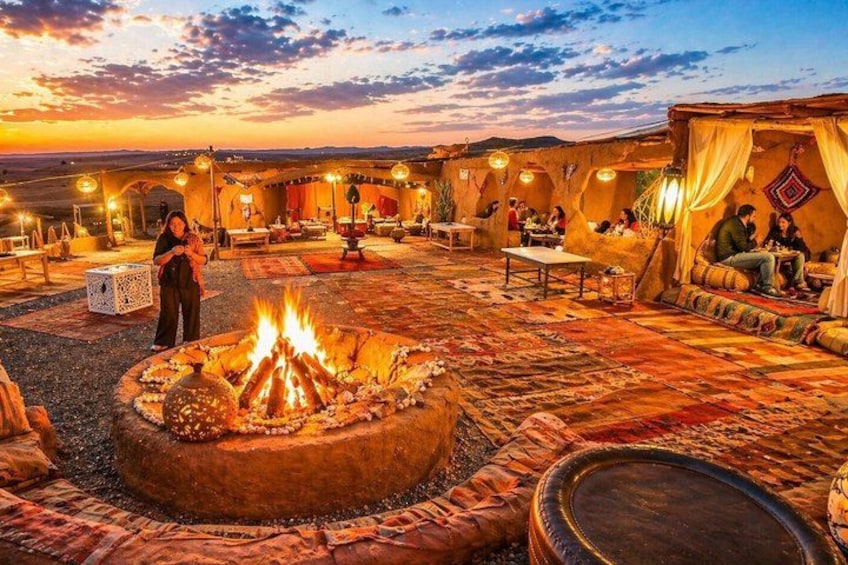 An outdoor seating area with a fire pit, tables, and people dining. 1
