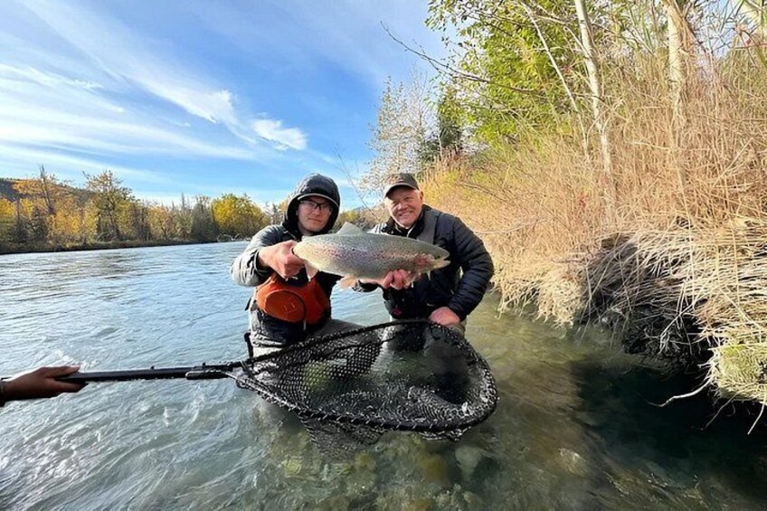 Dos personas en un río sosteniendo un pez. 2