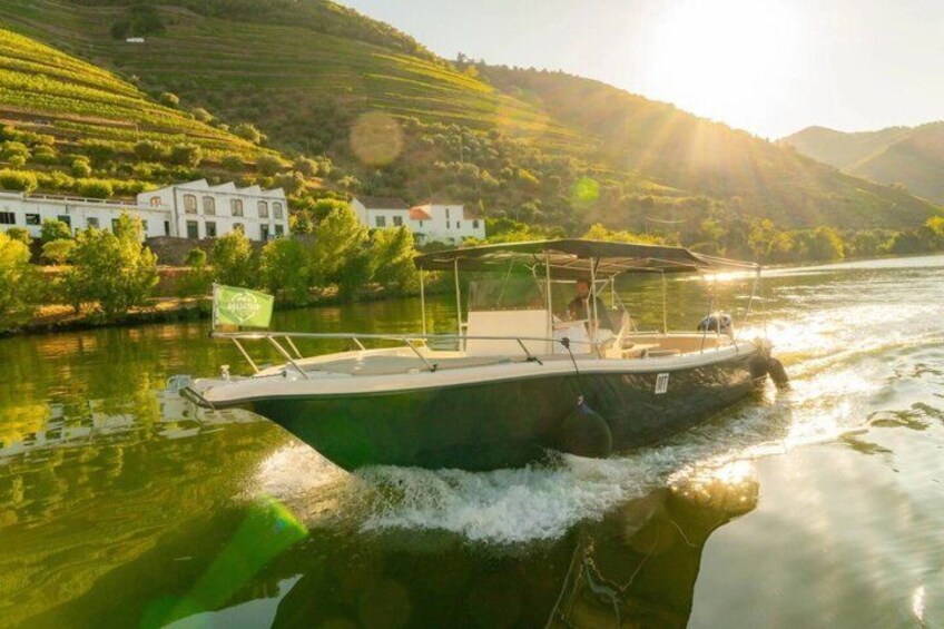 A green boat on a river with buildings and hills in the background. 2
