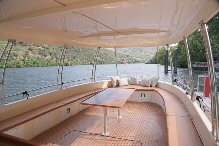 A boat deck with a wooden table, cushioned seating, and a canopy. 3