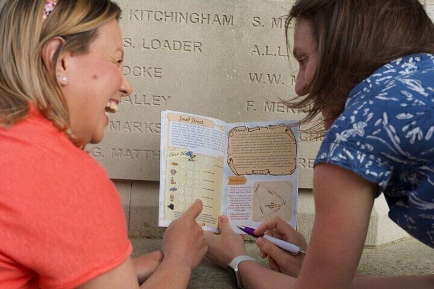 Two people examining a historical plaque with names and dates. 3