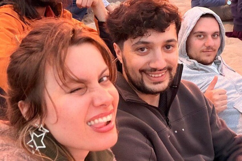 A group of people sitting outdoors, some wearing hoodies. 2